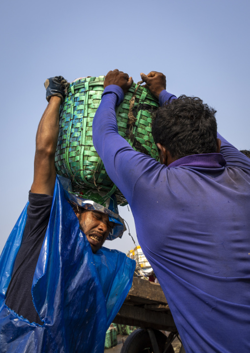 A bangladeshi porter carries a load at the morning fish market, Chittagong Division, Chittagong, Bangladesh