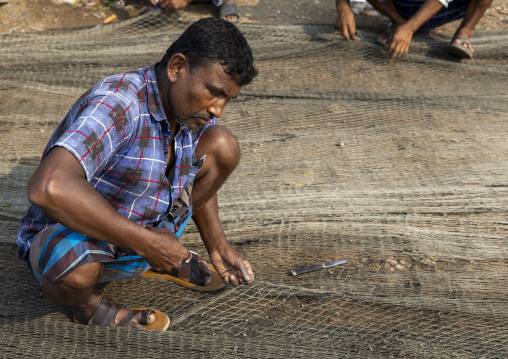 Bangladeshi man repairing his net in the fish market, Chittagong Division, Chittagong, Bangladesh