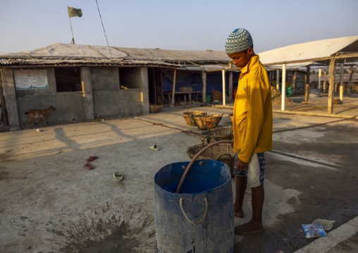 Bangladeshi boy filling a barrel with water in a fishery, Chittagong Division, Cox's Bazar Sadar, Bangladesh