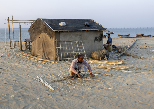 Bangladeshi man repairing a bamboo hut on the beach, Chittagong Division, Cox's Bazar Sadar, Bangladesh