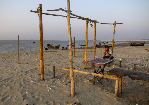 Bangladeshi man sit in an abandonned cafe on the beach, Chittagong Division, Cox's Bazar Sadar, Bangladesh