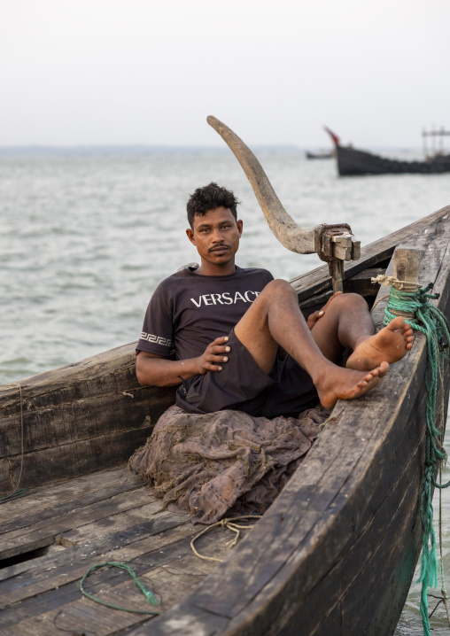 Bangladeshi man resting on a moon fishing boat, Chittagong Division, Cox's Bazar Sadar, Bangladesh