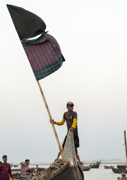 Bangladeshi man holding a flag on a moon fishing boat, Chittagong Division, Cox's Bazar Sadar, Bangladesh