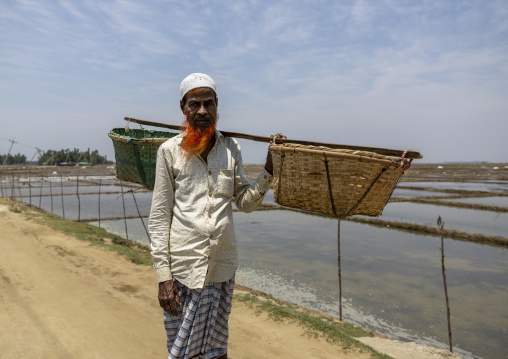 Bangladeshi man collecting salt in baskets, Chittagong Division, Maheshkhali, Bangladesh