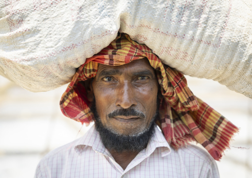 Portrait of a bangladeshi man carrying salt bag on the head, Chittagong Division, Maheshkhali, Bangladesh