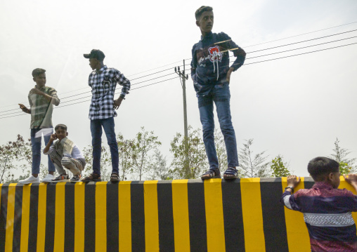 Teenage boys standing on a road divider, Chittagong Division, Chittagong, Bangladesh