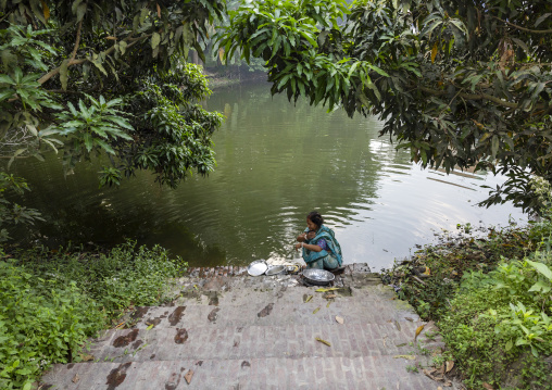 Bangladeshi woman cleaning cooking dishes in a pond, Dhaka Division, Tongibari, Bangladesh