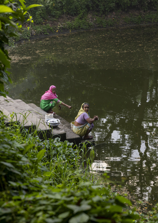 Bangladeshi women cleaning cooking dishes in a pond, Dhaka Division, Tongibari, Bangladesh