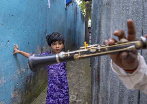 Bangladeshi girl in the street looking at a musician playing trumpet, Dhaka Division, Munshiganj Sadar, Bangladesh