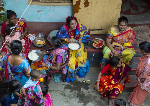 Hindu women eating in a courtyard at Lal Kach festival, Dhaka Division, Munshiganj Sadar, Bangladesh