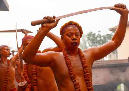 Hindu devotee with a sword covered with orange color at Lal Kach festival, Dhaka Division, Munshiganj Sadar, Bangladesh