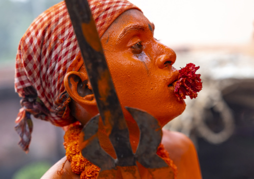 Hindu devotee with a sword covered with orange color at Lal Kach festival, Dhaka Division, Munshiganj Sadar, Bangladesh