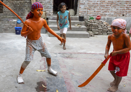 Young hindu devotees in orange color playing with swords at Lal Kach festival, Dhaka Division, Munshiganj, Bangladesh