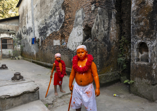 Young hindu devotees in orange color playing with swords at Lal Kach festival, Dhaka Division, Munshiganj, Bangladesh