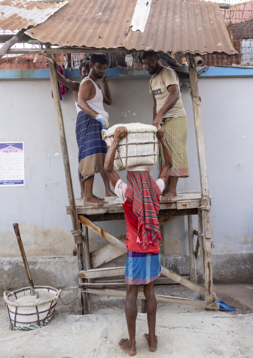 Bangladeshi men weighing baskets with salt at a factory, Chittagong Division, Chittagong, Bangladesh
