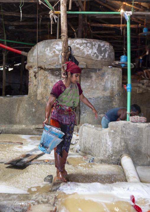 Bangladeshi woman washing salt in water in a factory, Chittagong Division, Chittagong, Bangladesh
