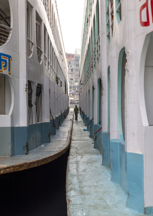 Man walking between two anchored ferry vessels at the dockyard, Dhaka Division, Dhaka, Bangladesh