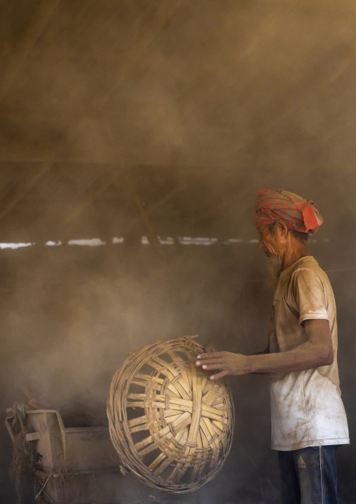Bangladeshi worker putting dried tobacco leaves in grinder, Rangpur Division, Rangpur, Bangladesh