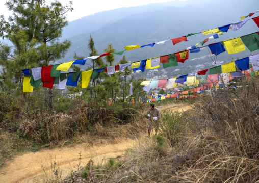 Bhutanese man under prayer flags, Chang Gewog, Thimphu, Bhutan