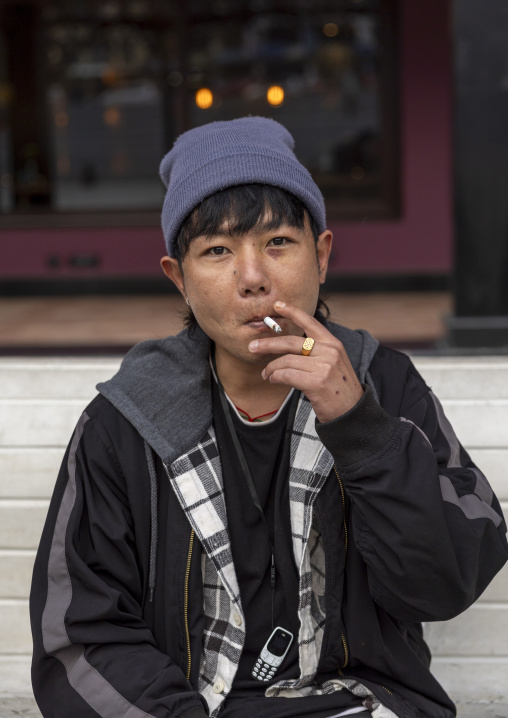Bhutanese young man smoking cigarette in the street, Chang Gewog, Thimphu, Bhutan