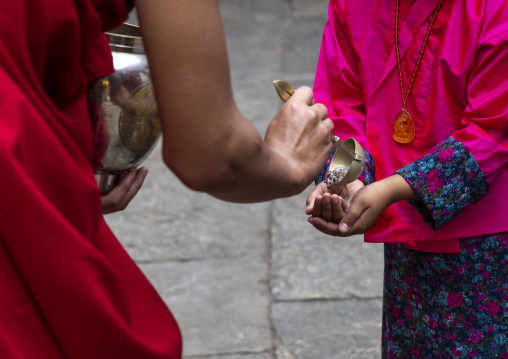 Monk giving black lentils with milk to pilgrims in Punakha dzong, Punakha dzongkhag, Punakha, Bhutan
