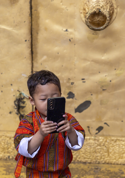 Butanese boy using a mobile phone in Punakha Dzong, Punakha dzongkhag, Punakha, Bhutan