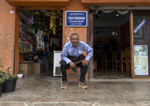 Bhutanese man sit at entrance of a shop, Thedtsho Gewog, Wangdue Phodrang, Bhutan