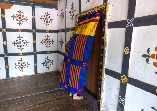 Monk closing a door hidden by a curtain in Nyenzer Lhakhang, Thedtsho Gewog, Wangdue Phodrang, Bhutan