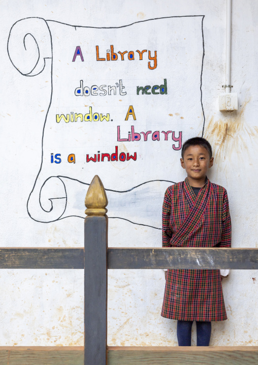 Portrait of a boy in front of a mural promoting books in Rubesa Primary School, Wangdue Phodrang, Rubesagewog, Bhutan