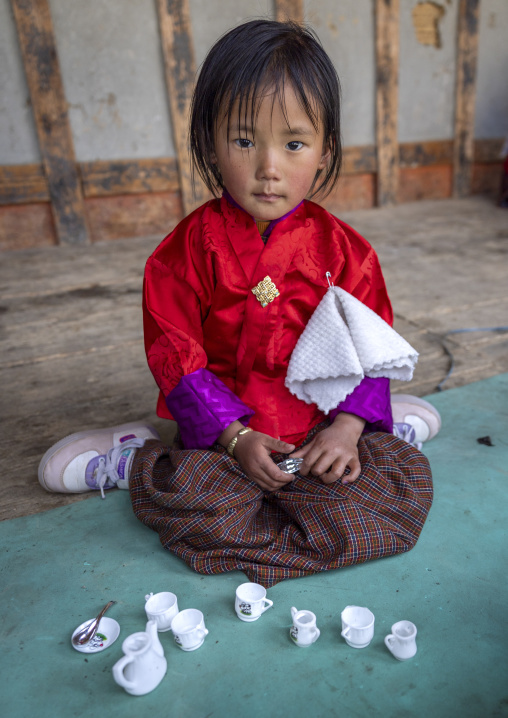 Bhutanese girl playing with tea cups toys  in Ura Lhakhang monastery, Bumthang, Ura, Bhutan