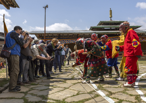 Masked atsaras with tourists at Ura Yakchoe festival, Bumthang, Ura, Bhutan