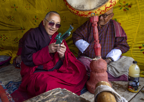 Monk with a gun toy in Ura Lhakhang monastery during festival, Bumthang, Ura, Bhutan