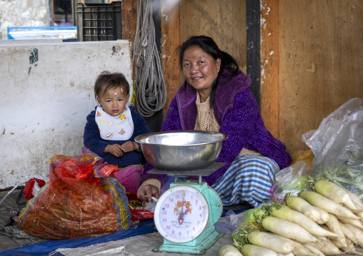 Bhutanese woman with her child selling vegetables in a market, Chhoekhor Gewog, Bumthang, Bhutan