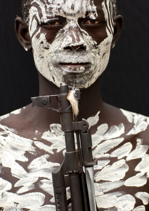 Karo man tribe with white painted chest and kalashnikov, Omo valley, Korcho, Ethiopia
