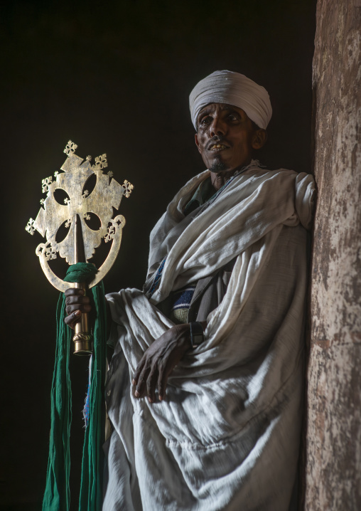 Orthodox priest holding a cross inside a rock church, Amhara region, Lalibela, Ethiopia