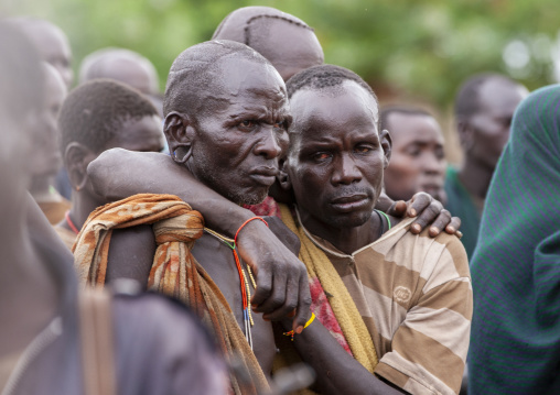 Suri tribe men holding eachother at a ceremony, Kibish, Omo valley, Ethiopia