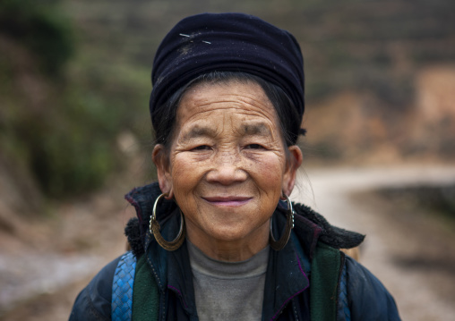 Smiling old black Hmong woman with hat and earrings, Lao Cai province, Sapa, Vietnam