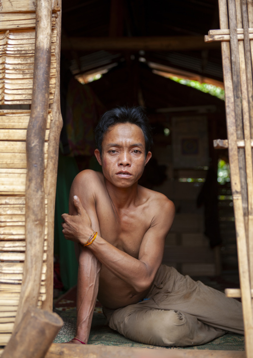 Alak man sit in the entrance of his bamboo house, Champassak province, Boloven, Laos