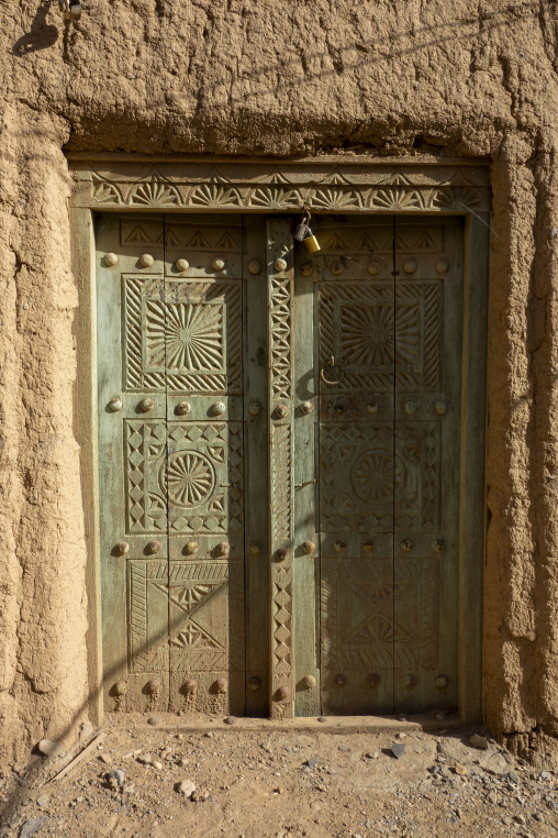 Ornately carved wooden double door secured with a padlock, Ad Dakhiliyah Region, Al Hamra, Oman