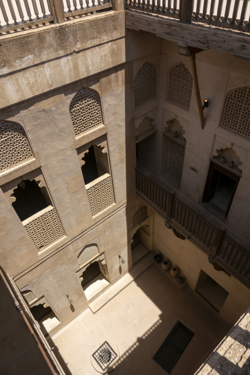 Elevated view of an interior courtyard surrounded by mudbrick walls with carved lattice windows and wooden balconies, Ad Dakhiliyah Region, Nizwa, Oman