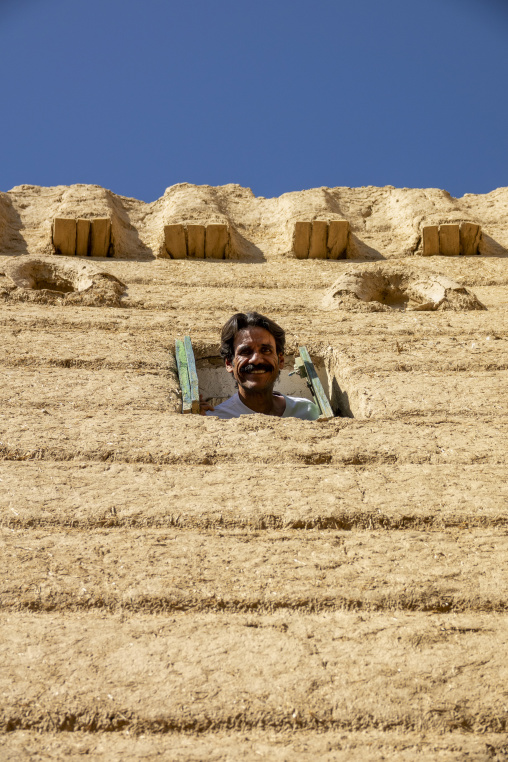 Man looking out from a window of a traditional mud house, Najran