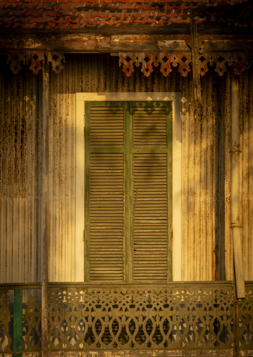 Weathered corrugated metal house facade with green shutters and ornate wooden fretwork, Benguela Province, Benguela, Angola