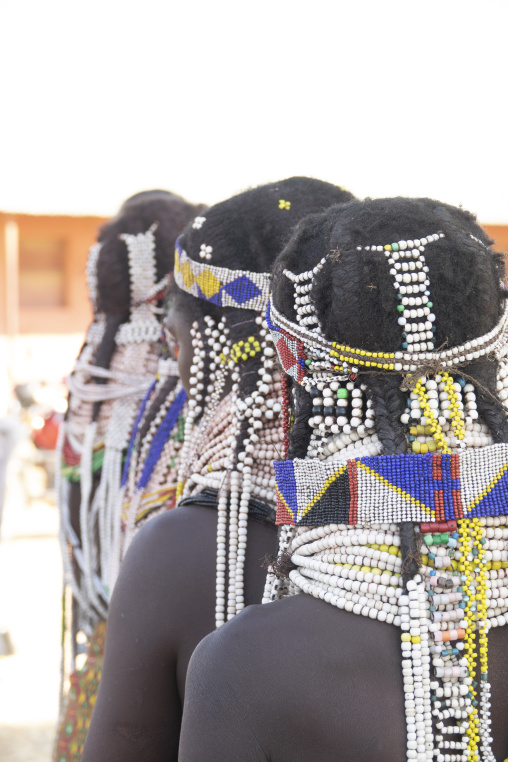 Three Handa women seen from behind wearing beaded headdresses and collars, Huila Province, Hoque, Angola