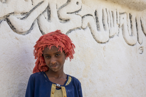 A young Sufi pilgrim wearing a red fabric headscarf poses for a close-up portrait, Oromia, Sheik Hussein, Ethiopia