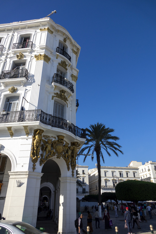 Ornate colonial-era building facade with gilded sculptures and wrought-iron balconies in a city square, North Africa, Algiers, Algeria