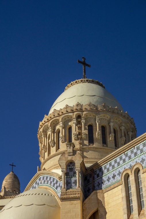 Ornate dome and cross of Notre-Dame d'Afrique basilica against blue sky, North Africa, Algiers, Algeria