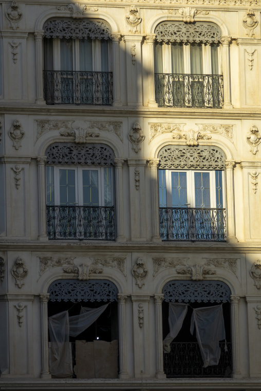 Close-up of ornate French colonial building facade with wrought-iron balconies and lace curtains, North Africa, Algiers, Algeria
