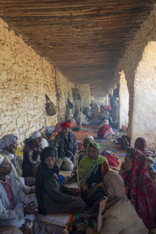 A group of Sufi pilgrims rests along a covered stone corridor at a shrine, Oromia, Sheik Hussein, Ethiopia