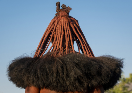 Rear view of a woman's head showing red ochre-coated hair strands over a thick black fiber fringe, Cunene Province, Oncocua, Angola