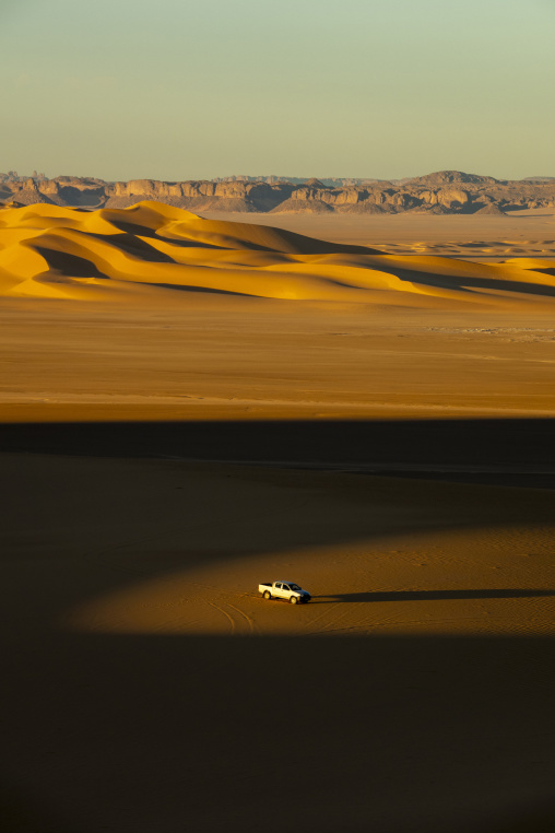 Aerial view of a pickup truck driving among sand dunes, North Africa, Erg Admer, Algeria